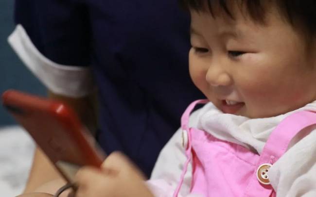 ▲刘月的女儿田野在手机上和爸爸交流。新京报记者 景如月 摄